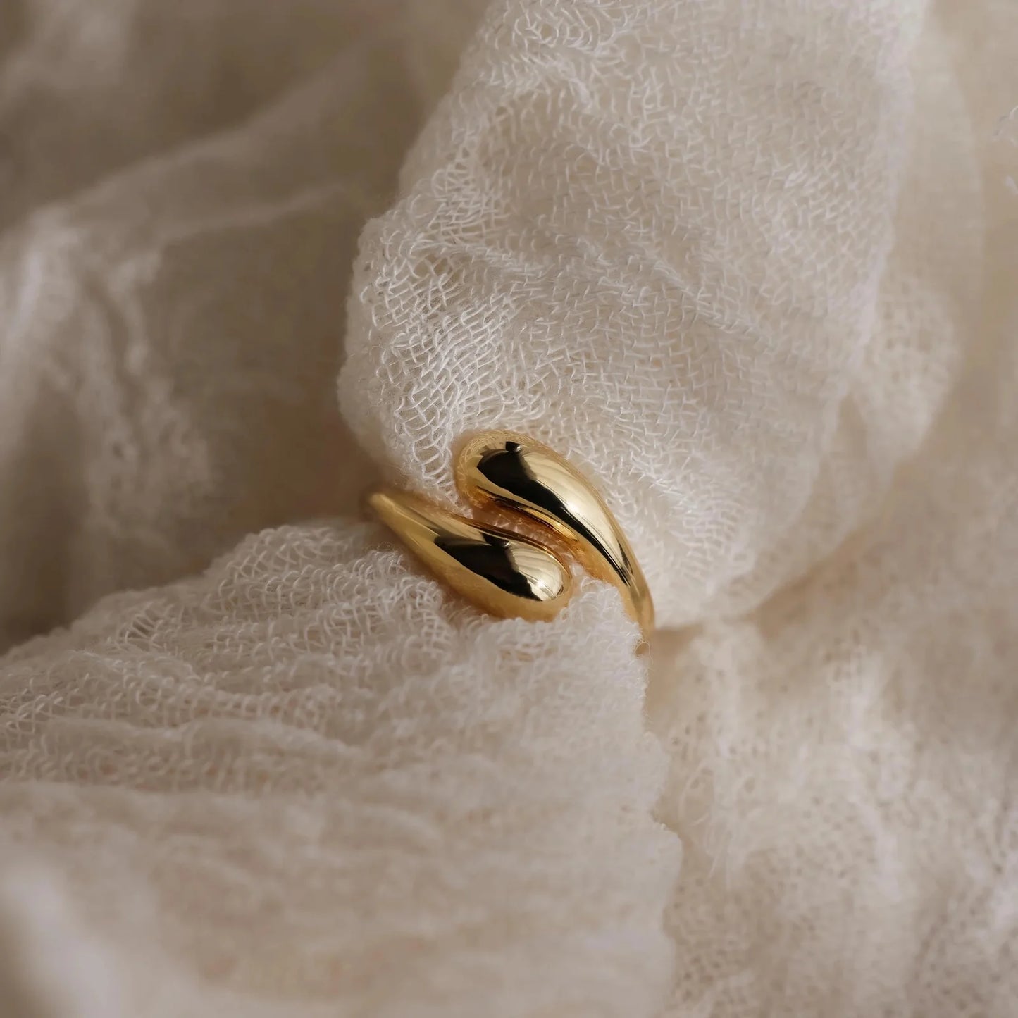Duo Dome Gold ring on a soft, beige fabric background