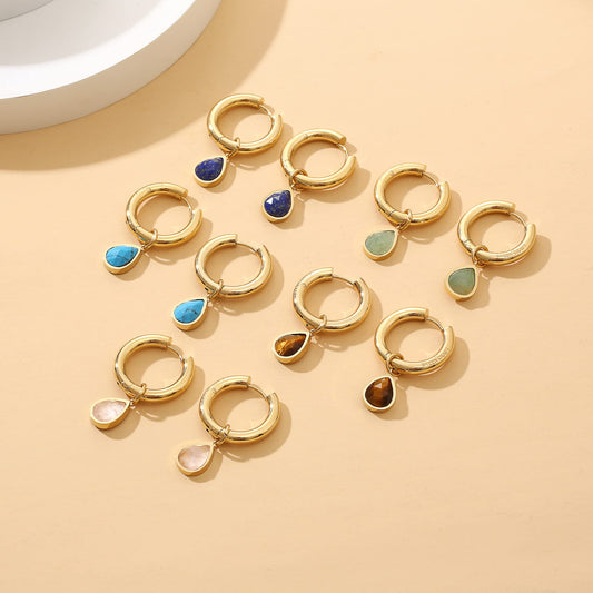 Gold hoop earrings with colorful rose quartz, tiger eye, green aventurine gemstones on a beige background