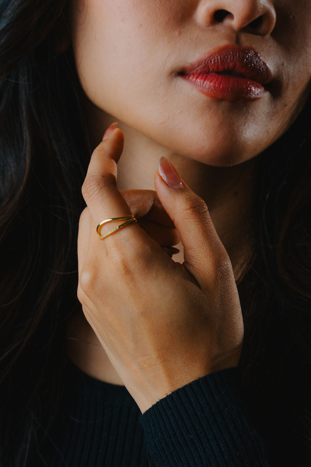 Close-up of a person's hand with Duo Wave Stacking gold Ring on a dark background