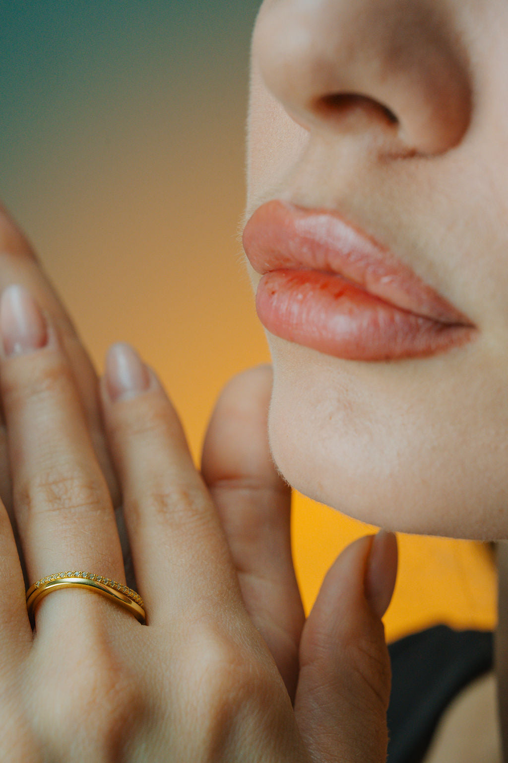 Close-up of a person's hand with a Duo Wave Stacking gold Ring and part of their face.