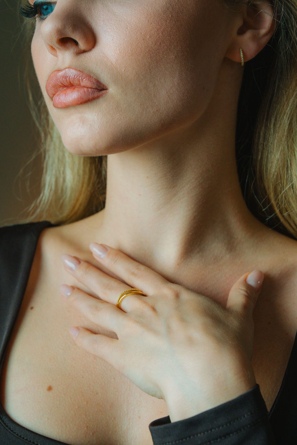 Close-up of a person wearing aDuo Wave Stacking gold Ring on their finger, with a neutral background.