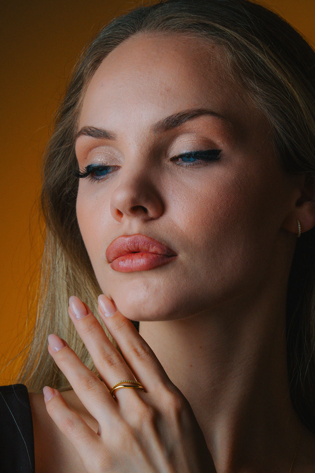 Duo Wave Stacking gold Ring Woman wear with blue eyeliner and pink lipstick against a warm-toned background
