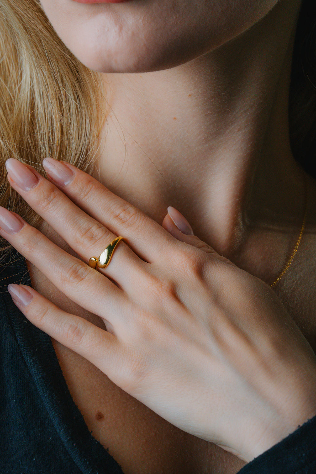 Close-up of a hand with Duo Dome Gold ring on a blurred background