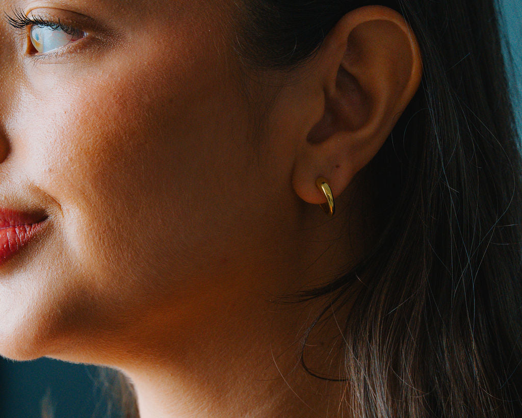 Close-up of a woman wearing a Gold Dome hoop earrings
