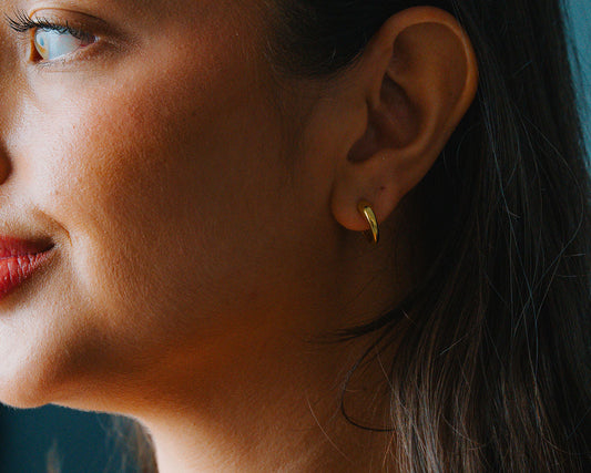 Close-up of a woman wearing a Gold Dome hoop earrings