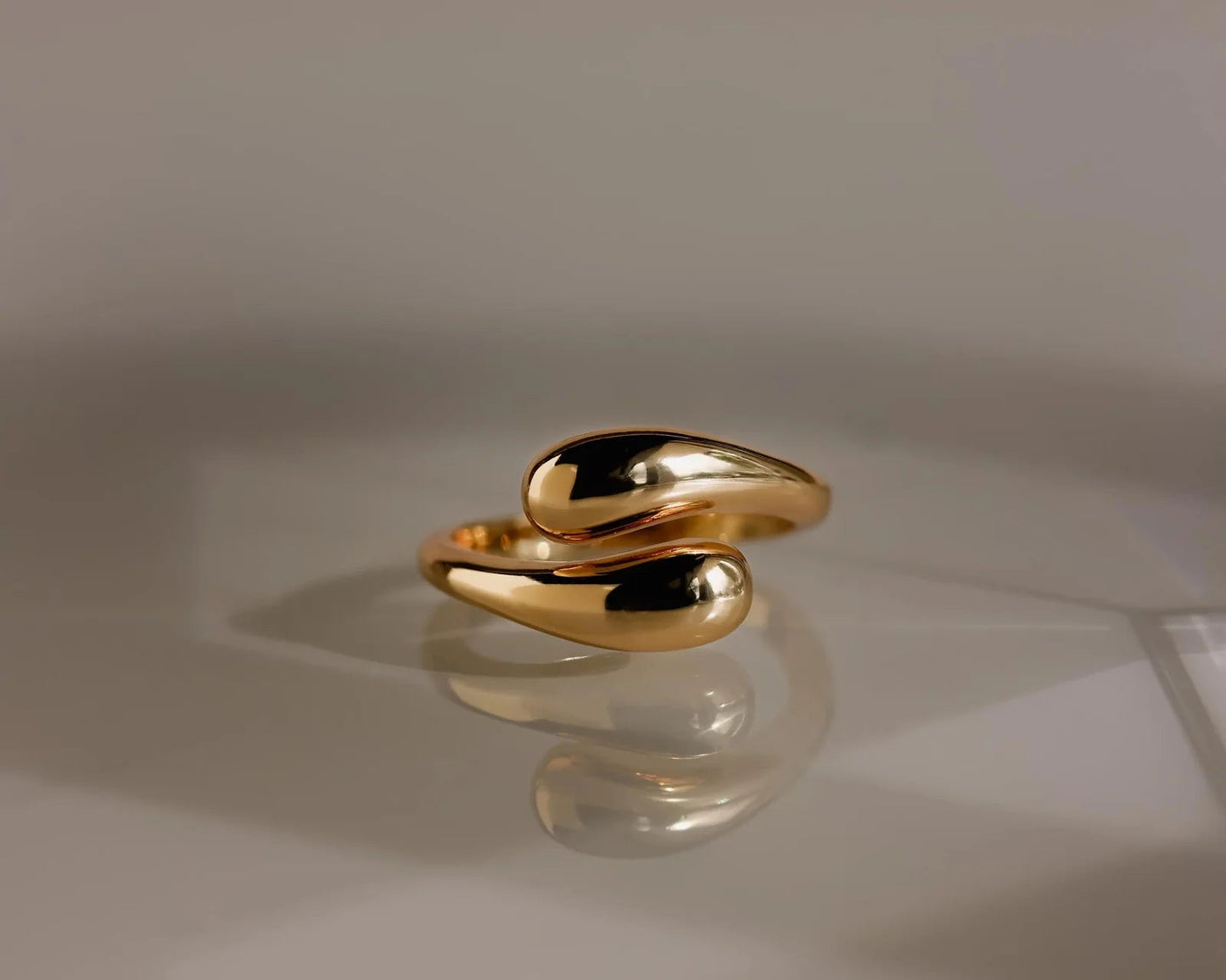 Duo Dome Gold ring on a reflective surface with a neutral background