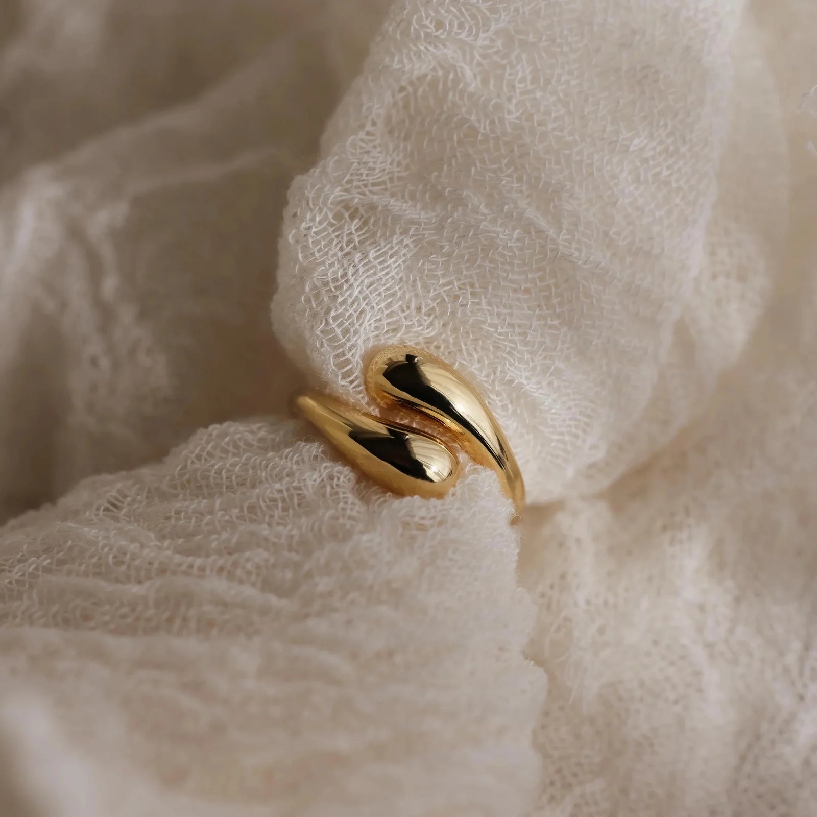 Duo Dome Gold ring on a soft, beige fabric background