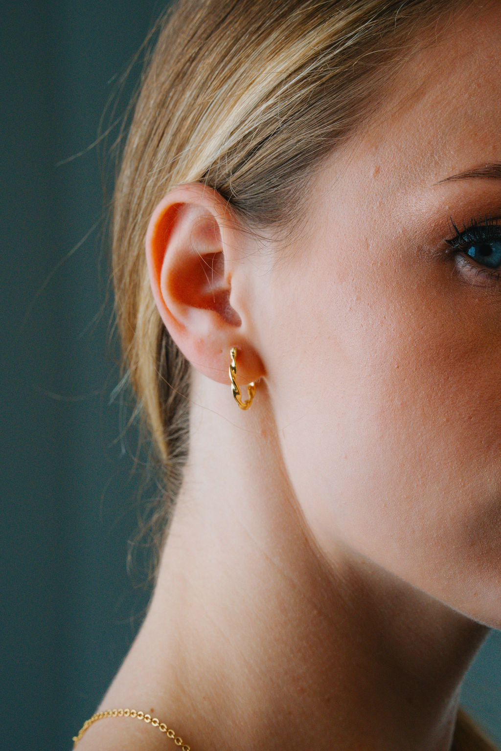Close-up of a person wearing Twisted Rope Large Hoop earrings with a blurred background